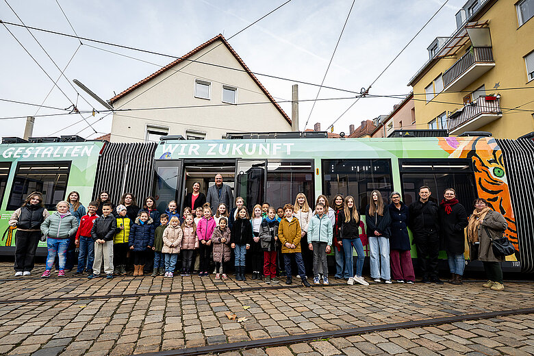 Die neue Tiergartenstraßenbahn mit den Gewinnerkinder und -jugendlichen und den Mitgliedern der Jury im Vordergrund.