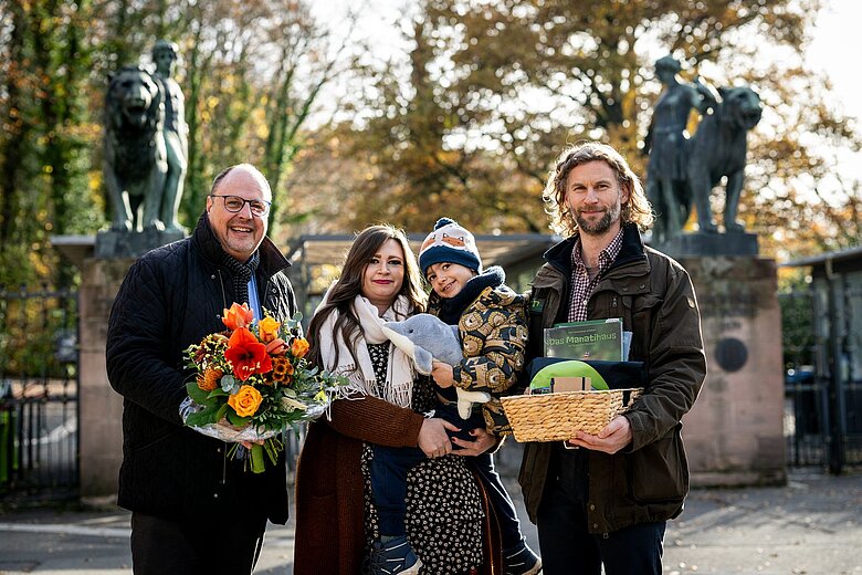 Bürgermeister Christian Vogel und Jörg Beckmann, stellvertretender Direktor und Biologischer Leiter des Tiergartens, begrüßen mit Sonja aus Nürnberg die millionste Tiergarten-Besucherin des Jahres 2025. 
