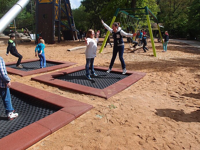 Fünftklässler_innen der Reichelsdorfer Mittelschule Nürnberg probieren die Sprungfelder auf dem neuen Jako-o-Spielplatz aus