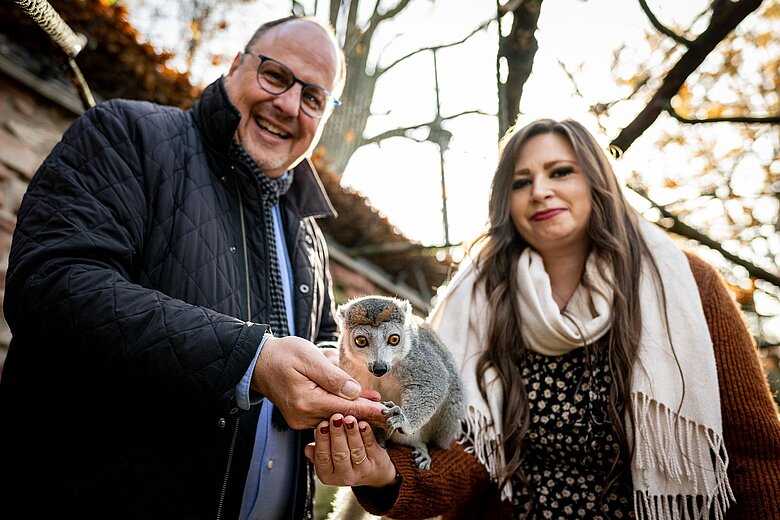 Bürgermeister Chrsitian Vogel und die millionste Besucherin des Tiergartens fürttern einen Kronenmaki.