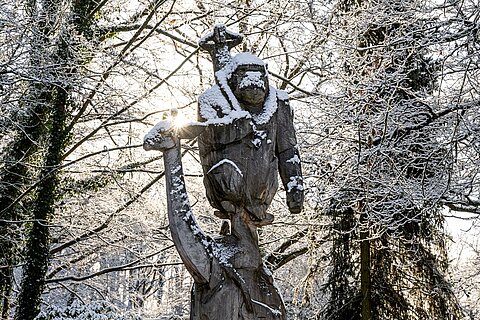 Eine schneebedeckte Holzstatue im Eingangsbereich des Tiergarten Nürnberg.