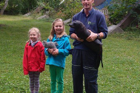 Tierpfleger Andreas Fackel mit dem Seelöwenjungtier Mia und Lea Nettersheim (Mitte), Namensgeberin für den kleinen Seelöwen. Links ihre Schwester Johanna Nettersheim. 