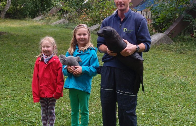 Tierpfleger Andreas Fackel mit dem Seelöwenjungtier Mia und Lea Nettersheim (Mitte), Namensgeberin für den kleinen Seelöwen. Links ihre Schwester Johanna Nettersheim. 